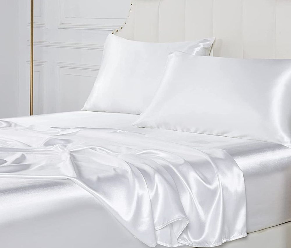 White silk bedding set featuring luxurious satin sheets and pillowcases on a bed, displaying the smooth, glossy texture characteristic of silk fabric that helps prevent skin irritation and allergies