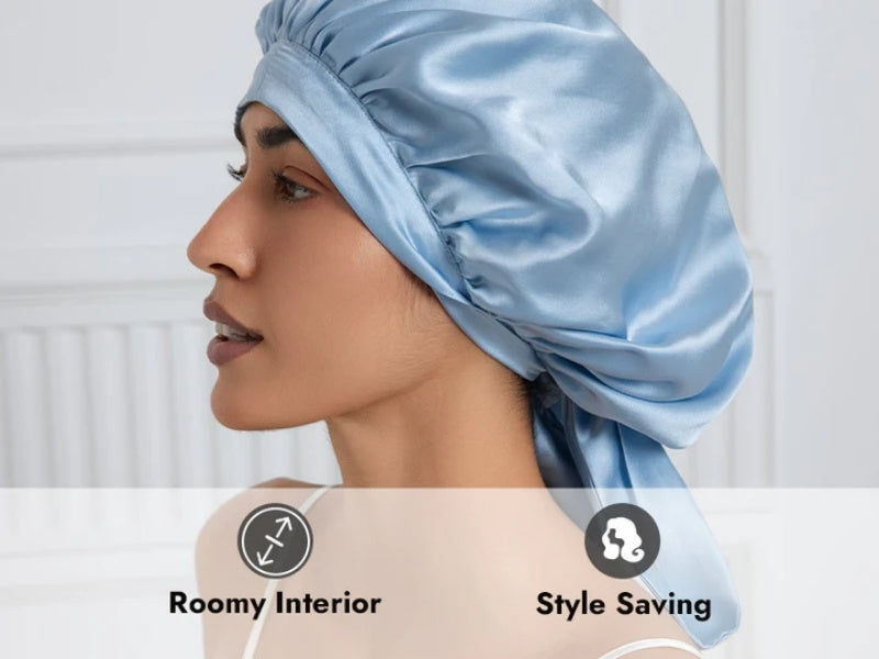 Profile view of a person wearing a light blue silk sleep bonnet/cap with text highlighting two key features: 'Roomy Interior' and 'Style Saving'