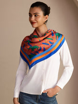 [Clay Elephant] Coral pink square scarf with blue, green and brown animal motifs, blue border, styled front, at neck, hand in pocket. 002