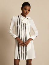 [White] Three-quarter frame: white long-sleeve tunic mini dress with vertical black stripes, with the side profile visible. 003