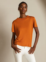 [Orange] Shown from the front at full length, orange crew-neck top with white trousers reveals its overall cut and lower edge. 005
