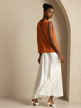 [Orange] Rear studio view of a model wearing an orange sleeveless cowl-neck top with a white maxi skirt. 002
