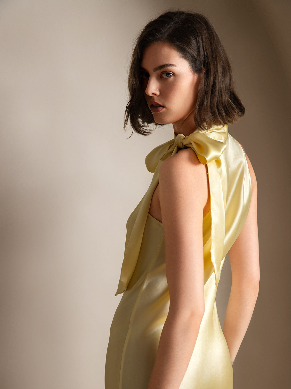 [Light Yellow] Rear studio view of a model wearing a pale yellow sleeveless maxi dress with a tied scarf neckline. 002