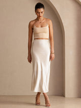 [Beige] Cream glossy maxi skirt on a model in a full-body front view with one foot forward and arms relaxed. 005