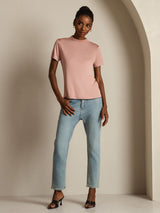 [Pink] The front of blush-pink crew-neck top with light blue jeans is visible as the model rests one hand along the waistline. 007