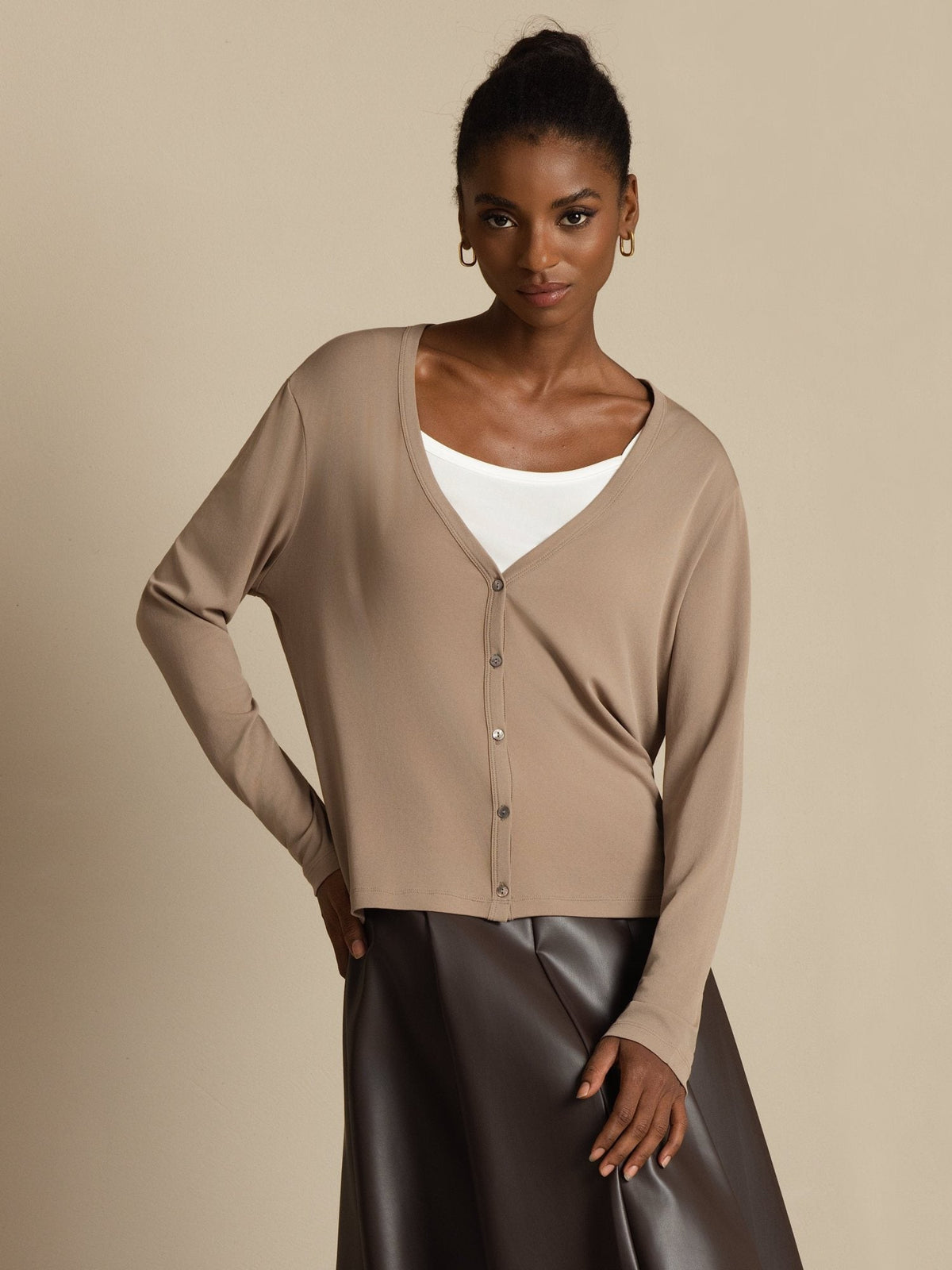 [Tan] Front mid-length view: beige button-front cardigan, white camisole, and dark brown maxi skirt, with one arm bent. 001
