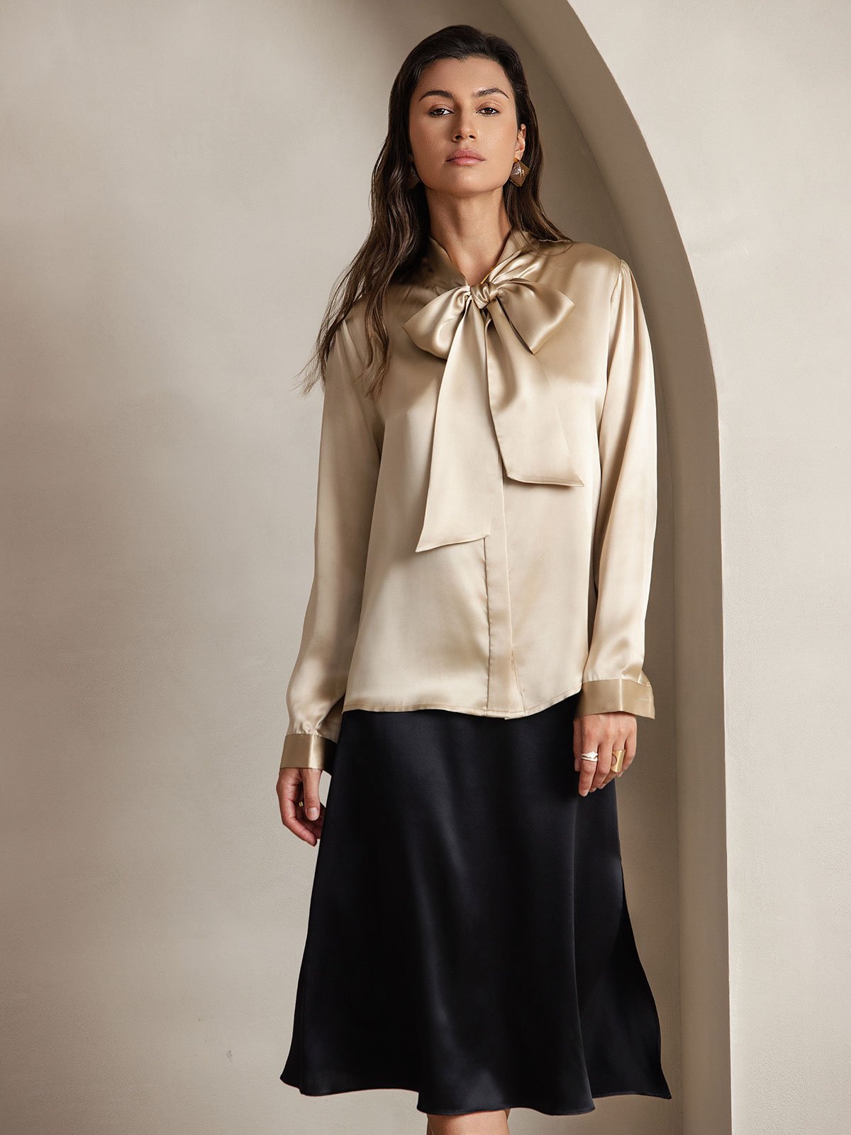 [Champagne] Champagne beige long-sleeve blouse with a large tie-neck bow, full front view, model standing with both arms relaxed. 001