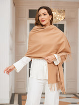 [Tan] tan beige rectangular shawl with fringed edges, styled front view, draped over the shoulders with hand holding an edge. 004