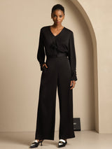 [Black] A full-body view presents black wide-leg trousers with a black blouse, with one leg set ahead to show the lower drape. 006