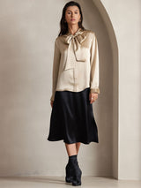 [Champagne] Champagne beige long-sleeve blouse with large tie-neck bow, full front view, arms down and gaze toward camera. 006