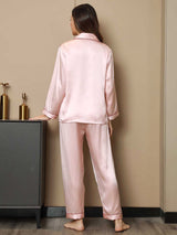 [Pink] Full-length back view of women's silk pajamas with a long-sleeve button-front top in light blush pink with dark piping 002