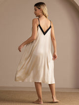 Full-body back studio view of a model wearing ivory V-neck slip nightgown with black trim.