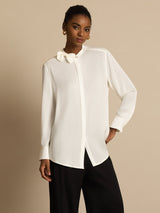 [White] White long-sleeve collared blouse with black wide-leg trousers in a front crop to thighs, one hand resting at the hip. 004