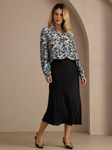 [Black] Three-quarter full-body front studio view of a model wearing black glossy maxi skirt. 007