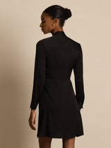 [Black] Rear studio view of a model wearing a black long-sleeve tunic mini dress with vertical white stripes. 002