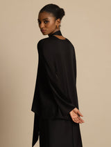 [Black] Rear studio view of a model wearing a black draped-neck long-sleeve blouse with a black skirt. 002