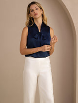 [Dark Blue] Navy blue sleeveless tie-neck top on a model in a mid-length front view with both hands loosely held at her waist. 006