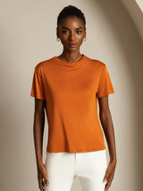 [Orange] Side-angled view: orange short-sleeve crew-neck top with white trousers, with the model partly turned. 003