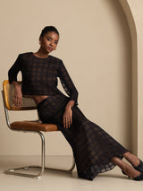 Model wearing black textured grid silk high-waist A-line skirt with matching top