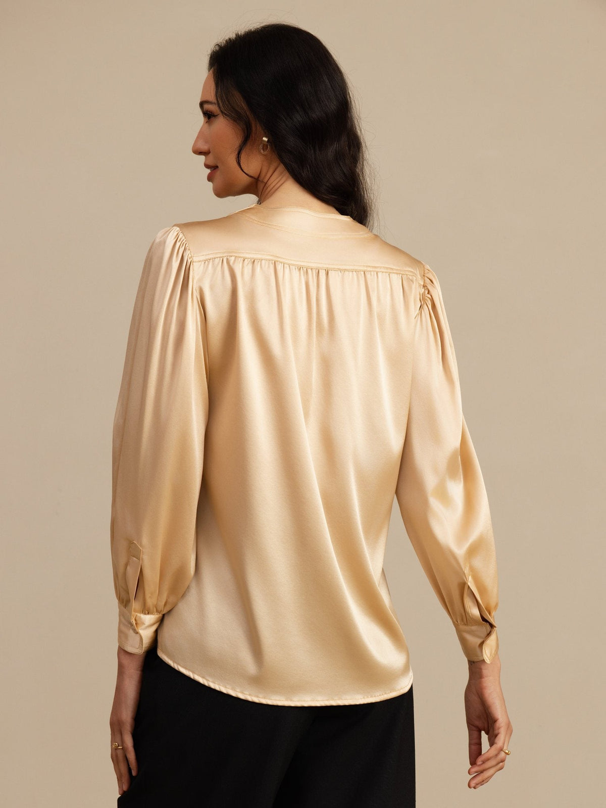 [Champagne] Mid-length side studio view of a model wearing champagne round-neck long-sleeve blouse. 002