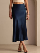 [Dark Blue] Navy blue glossy maxi skirt on a model in a waist-to-ankle front crop with one foot crossed ahead of the other. 004