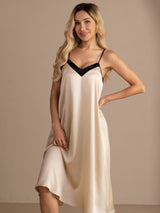 Ivory V-neck nightgown with black trim in a knee crop, one hand on her hip and one at the hem.