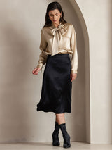 [Champagne] Champagne beige long-sleeve blouse with a large tie-neck bow, full front view, model stepping forward with arms relaxed. 004
