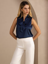 [Dark Blue] Three-quarter mid-length front studio view of a model wearing navy blue sleeveless tie-neck blouse. 004