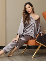 [Gray] silver gray long-sleeve buttoned pajama set with piping, seated front view, model leaning back in a chair. 009