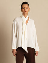 [White] White draped-neck long-sleeve blouse with dark brown wide-leg trousers in an angled view, with the model turned. 003