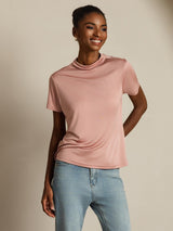 [Pink] Blush-pink crew-neck top with light blue jeans in a front crop to upper thighs, hand behind back, the other down. 006