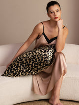 [Leopard] Tan, black and brown leopard-print square pillowcase, seated product view, elbow on pillow, chin on fist. 004