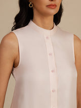 [Pink] Close upper-body view of a blush-pink sleeveless drop-waist dress, showing the band collar and button placket. 004