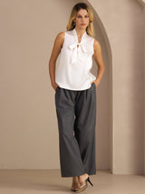 [White] White sleeveless tie-neck top on a model in a full-body front view with one hand at her hip and weight shifted. 006