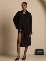 [Black] Complete body view: black draped-neck long-sleeve blouse with a black skirt, with weight shifted sideways. 006