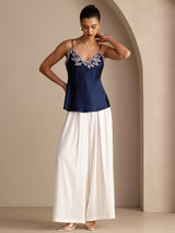 [Dark Blue] Navy blue camisole with slim straps and pale floral-lace V-neck, full front view, one hand lifted beside the neck. 007