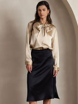 [Champagne] Champagne beige long-sleeve tie-neck blouse with bow, front crop from head to below black skirt, both arms down. 005