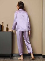 [Lavender] Full-length back view of women's silk pajamas with a long-sleeve button-front top in lavender purple with dark piping 002