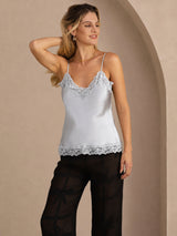[Grayish Blue] Pale blue lace-trim V-neck camisole top on a model in a mid-length front view with one hand raised to her hair. 001