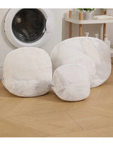 White mesh laundry wash bags in three sizes for delicate silk garment care beside a washing machine