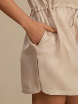 [Tan] Side-pocket detail of a silk cap-sleeve short dress with drawstring waist and side pockets in light tan 005