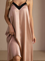 Close-up of blush pink V-neck slip nightgown with black trim, showing dark V-neck trim and a flowing midi hem.