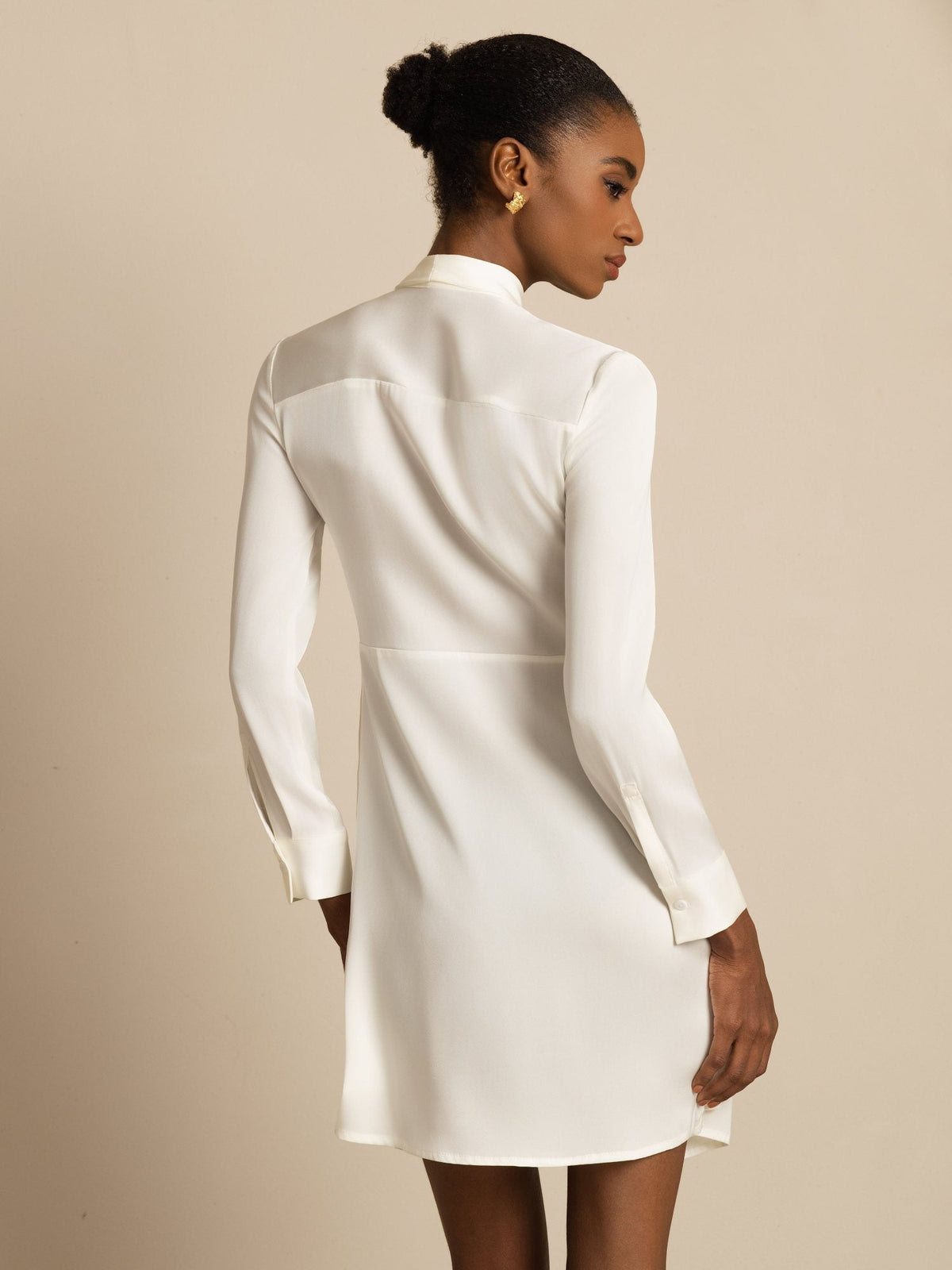 [White] Rear studio view of a model wearing a white long-sleeve tunic mini dress with vertical black stripes. 002