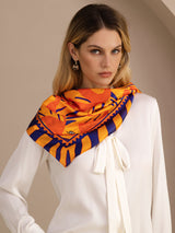 [Orange Dog] Orange, yellow and red animal-print square scarf with dark striped border, styled front, tied at neck, point on chest. 002
