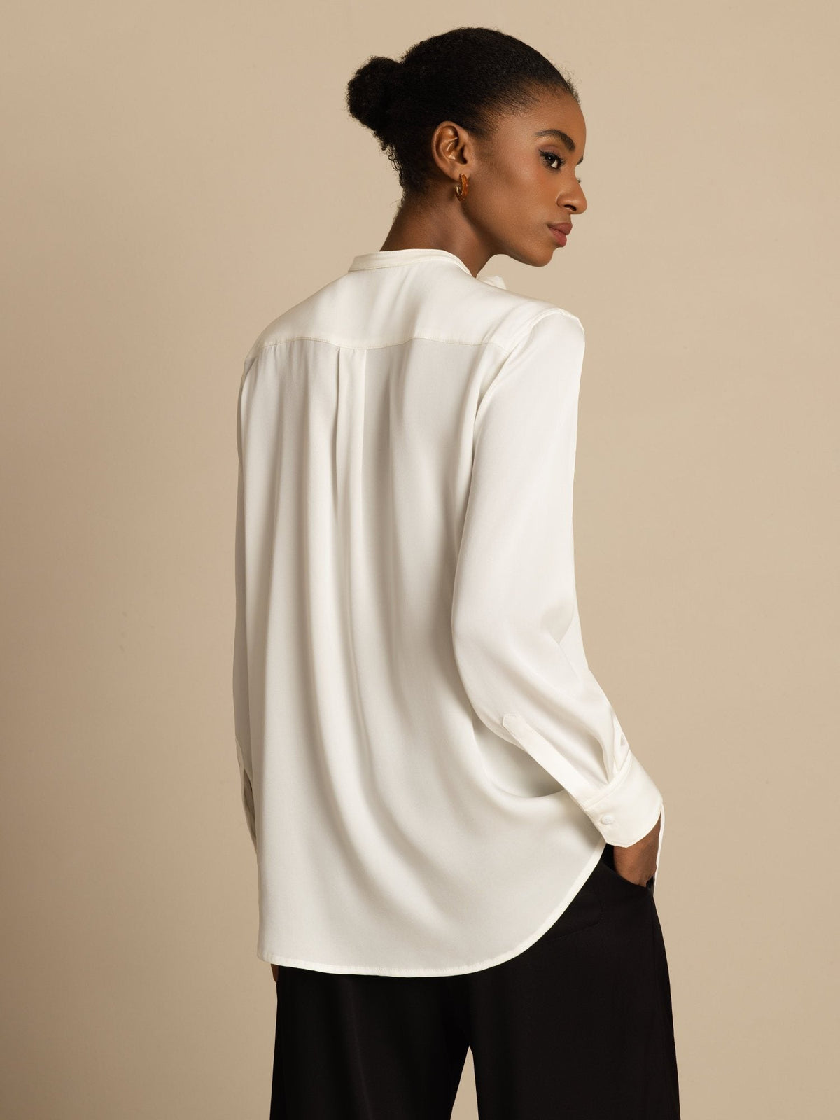 [White] Rear studio view of a model wearing a white long-sleeve collared blouse with black wide-leg trousers. 002
