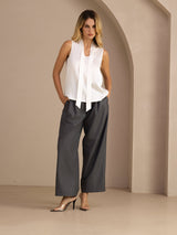 [White] White sleeveless tie-neck top on a model in a full-body front view with arms relaxed and feet close together. 007
