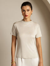 [Gray] Light gray short-sleeve crew-neck top with a white skirt in a front view cropped at the hips, both arms resting down. 006