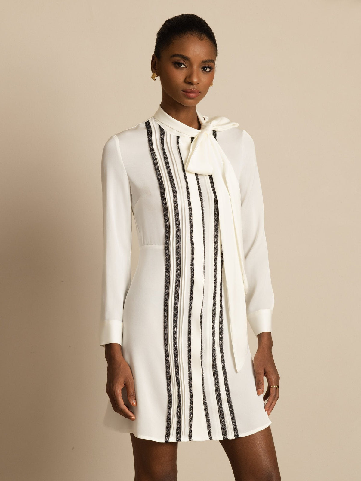[White] White long-sleeve tunic mini dress with vertical black stripes in a front view cropped at the thighs, arms down. 001