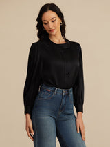 [Black] Black round-neck lantern-sleeve blouse on a model in a mid-length front view as she looks down toward the garment. 001