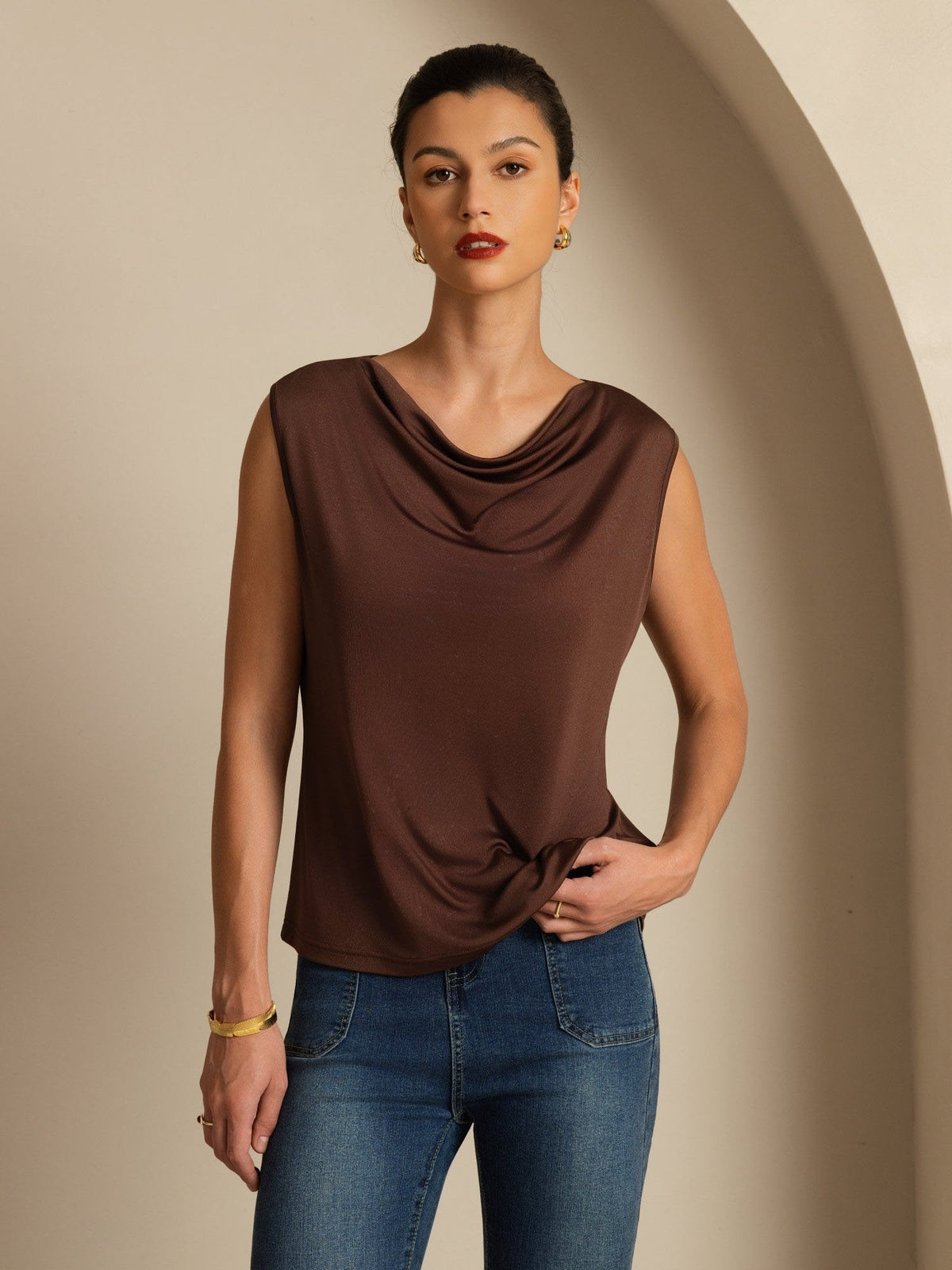 [Coffee] Coffee-brown cowl-neck top with blue jeans appears in a front mid-length crop, with one arm bent beside the torso. 001